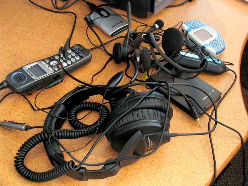 Various devices, including headphones, on top of a desk
